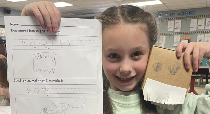 A first grader holds up her design project at JSA.
