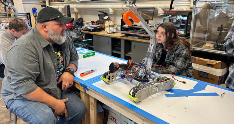 Metro Teacher and Student discuss a robot being constructed.
