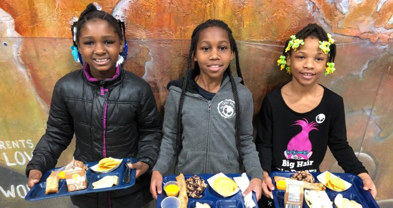 three students holding lunch trays