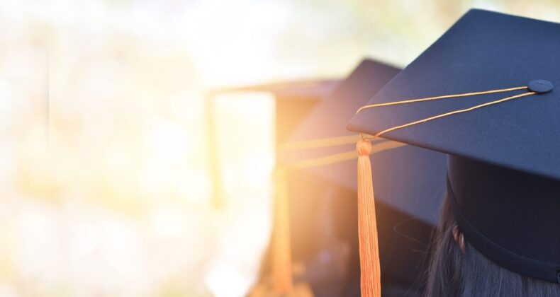 The back image of the graduates wearing a yellow tassel hat.