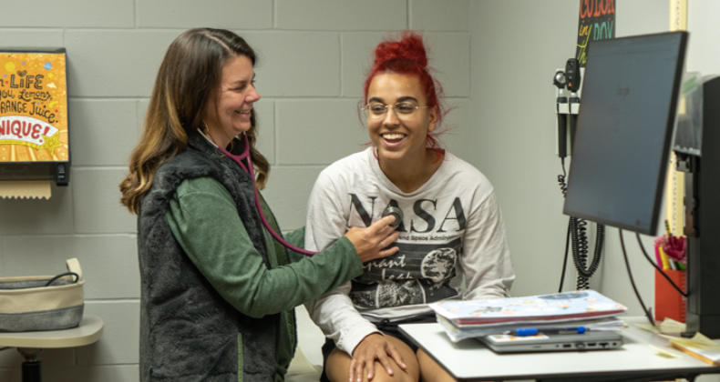 A nurse practitioner examines a student.