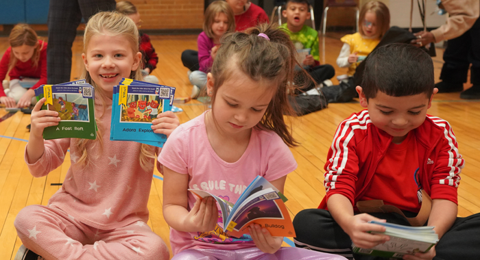 Three Hiawatha Elementary students show off their new decoder reading books.