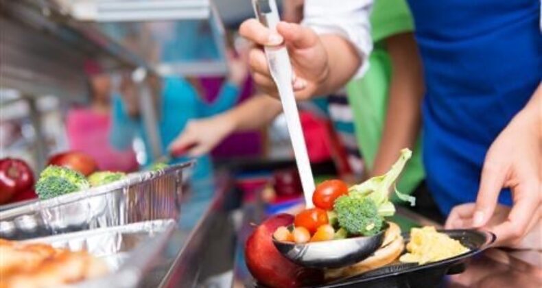 close-up of students scooping lunch onto their tray